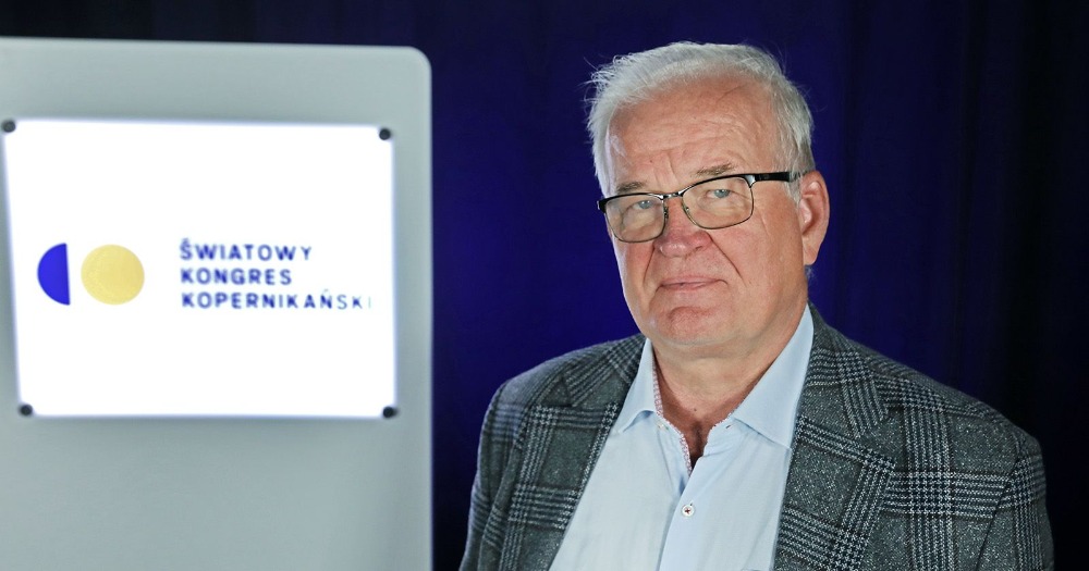 A man photographed half-body, next to him is a screen and the logo of the World Copernican Congress.