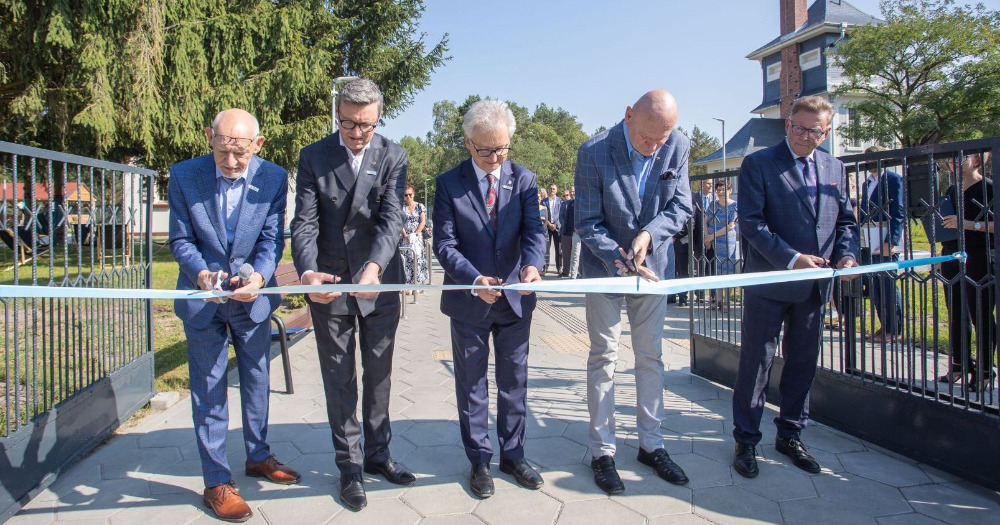 Five men cut the symbolic ribbon stretched across the entrance gate to the Center. The cutting of the ribbon symbolizes the opening of the Center.